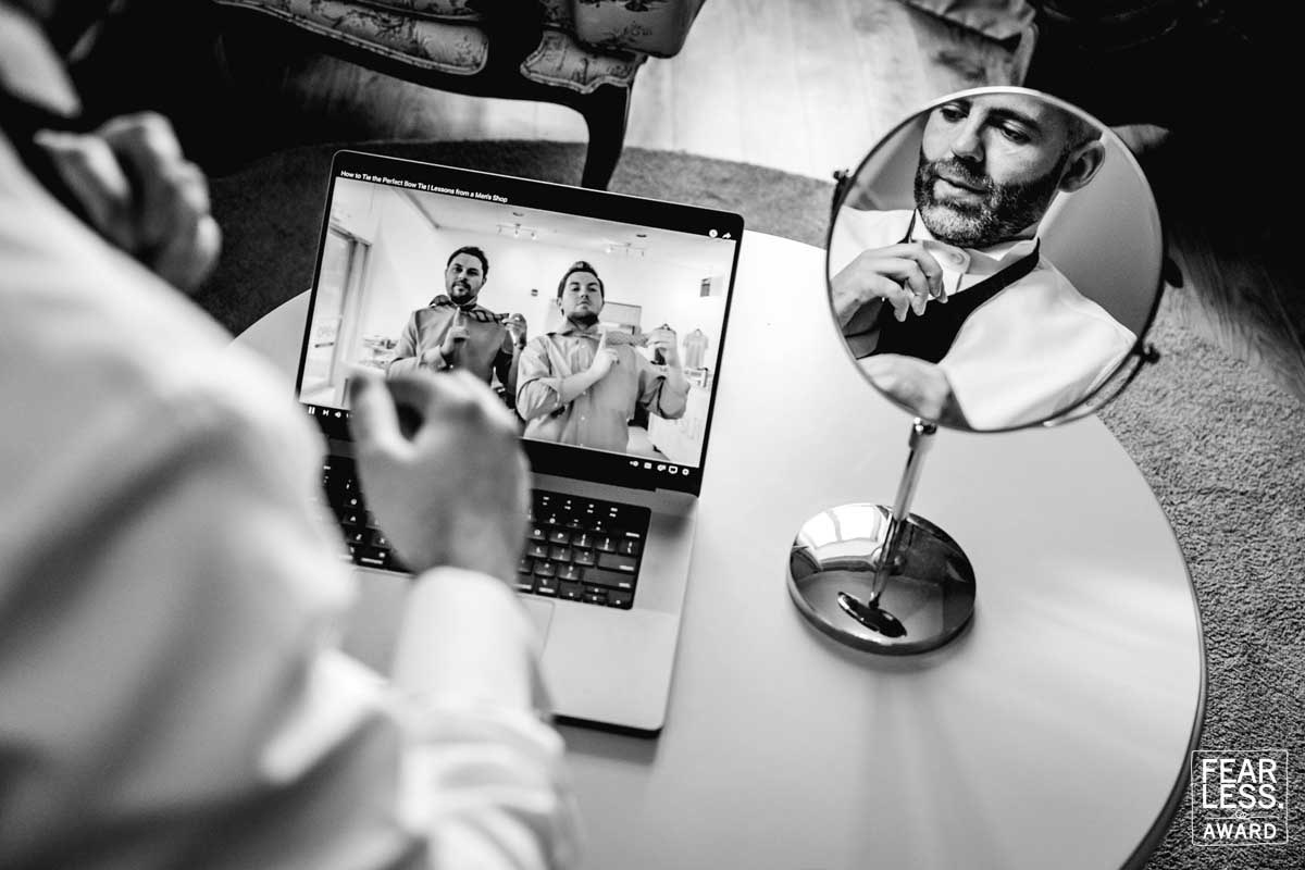 Reportage photo of the groom learning how to do his bow tie through youtube.