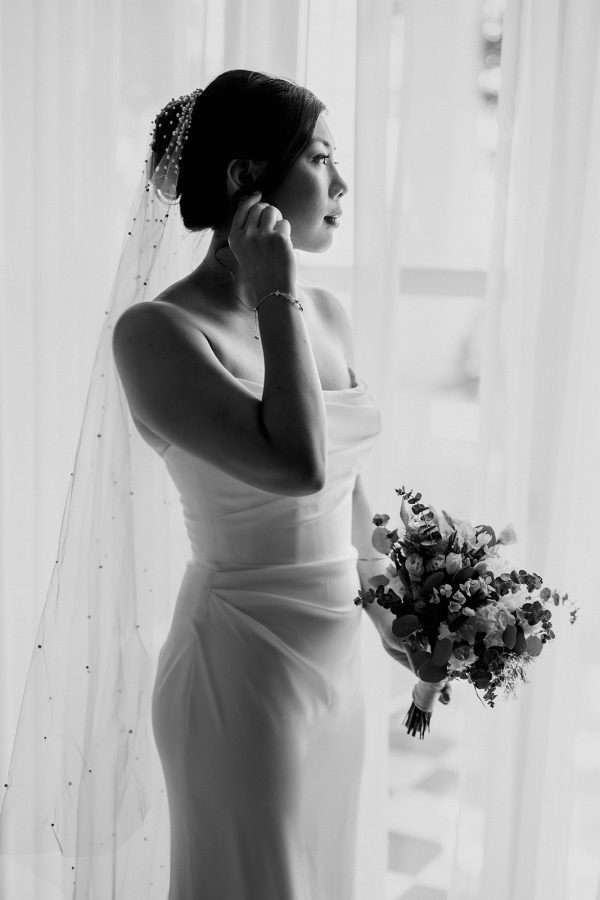 Bride getting ready by the window at Belmond Reids Palace, in Madeira Island, before an elegant destination wedding in Portugal photographed by Miguel Ponte.